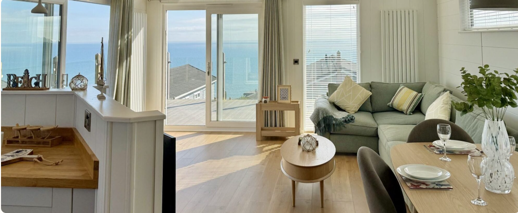 Bright open-plan lodge interior with sea view and modern coastal decor.
