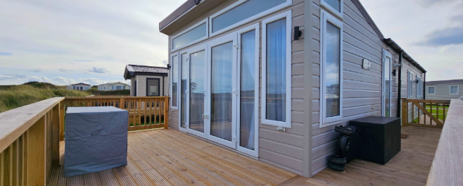 Holiday lodge with decking and covered hot tub on a coastal UK park